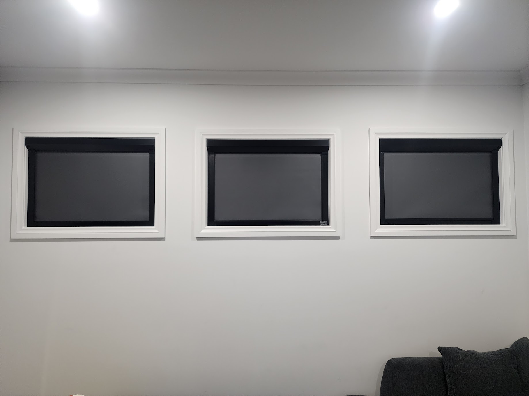 Three black framed Coverlight blinds fitted to the high windows in a home theatre room